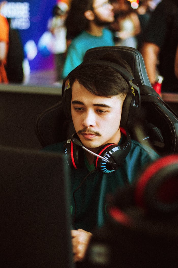 Young male gamer intensely focused at an esports tournament, wearing headphones.