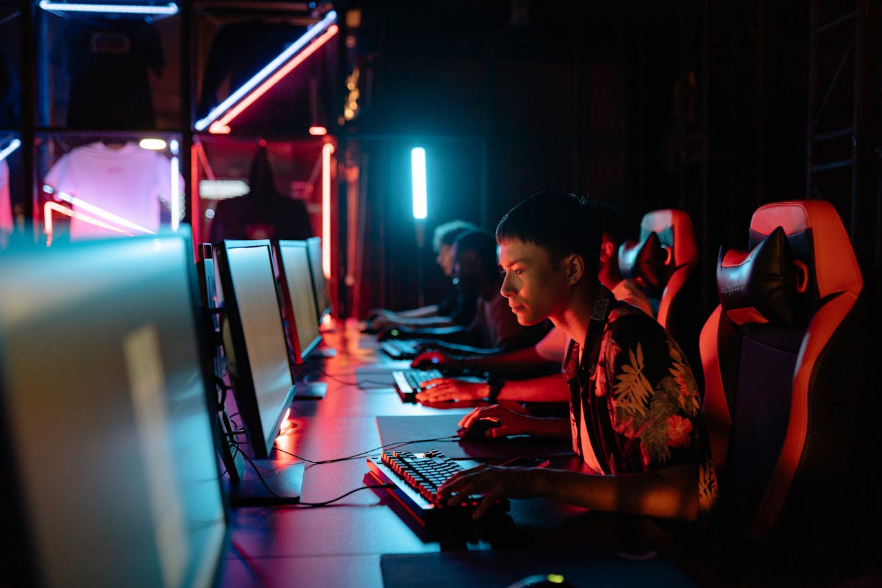 A group of focused gamers playing in a neon-lit gaming room, showcasing intense concentration and modern technology.